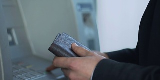 男性在自动柜员机插卡取现金并收到账户余额报告