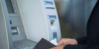 男性用手输入ATM键盘上的密码，从账户中取钱