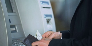 一名男子在ATM键盘上输入密码从银行账户中提取美元