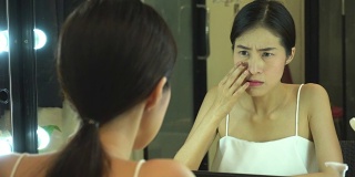 年轻的亚洲女孩与痤疮。肖像少女女性照镜子美容，护肤的生活理念
