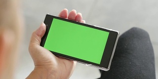 绿色屏幕显示的手机在金发女性的手中