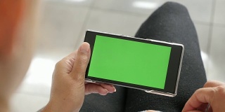 金发女性手握绿色屏幕手机展示