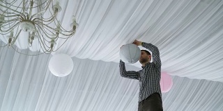 男人在天花板上挂着五颜六色的白粉灰纸灯笼。