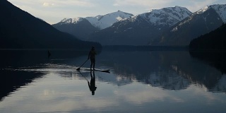 女子站起来划水板在一个原始的山湖