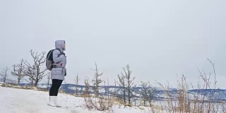 女人在贝加尔湖冰面上的旅行。闭关独特的佛塔布尔可汗纪念碑象征神秘的历史仪式岛大井山水山萨满教崇拜。冬岛之旅。
