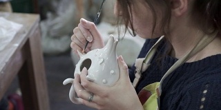 一位妇女正在装饰茶壶