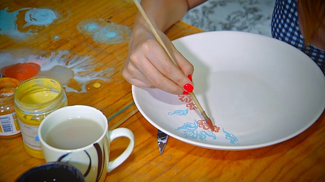 漂亮的年轻女子波特绘制一个粘土盘子。在陶器工作室工作的女人。小型企业