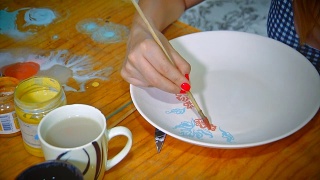 漂亮的年轻女子波特绘制一个粘土盘子。在陶器工作室工作的女人。小型企业视频素材模板下载
