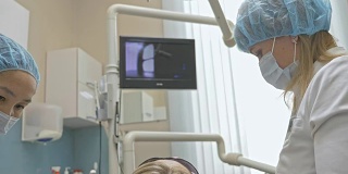 医生使用特殊的口腔内检查数码微型相机对牙齿进行检查。在监视器上，牙医和病人可以看到牙齿、牙齿问题的视频。牙医在现代牙科诊所里治疗病人。