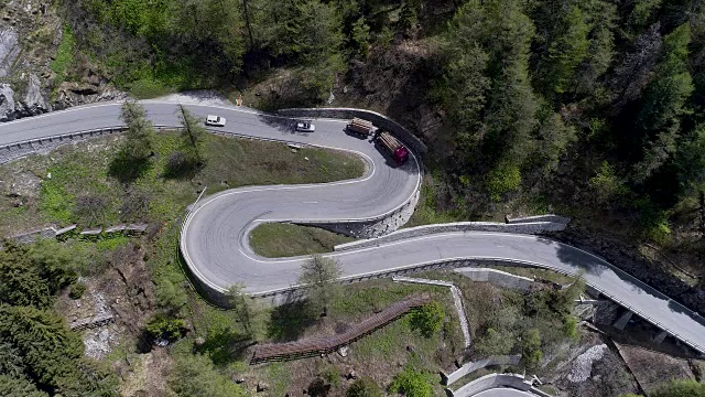 鸟瞰图山上蜿蜒的道路与卡车和汽车行驶在曲折起伏的欧洲瑞士4K