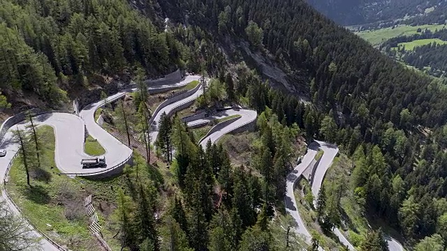 鸟瞰图山上蜿蜒的道路与卡车和汽车行驶在曲折起伏的欧洲瑞士4K