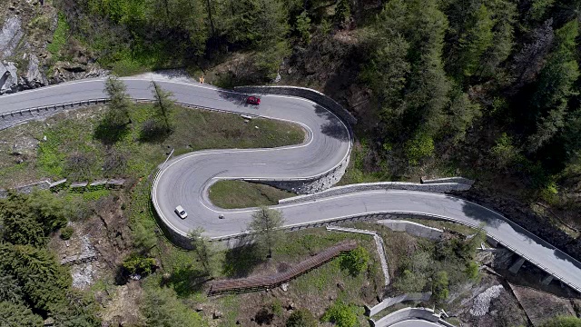 鸟瞰图山上蜿蜒的道路与卡车和汽车行驶在曲折起伏的欧洲瑞士4K