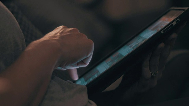 一张已婚妇女深夜在家里使用平板电脑的照片。