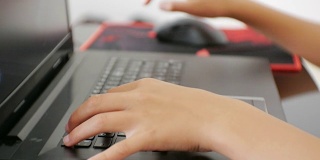 青少年使用笔记本电脑。少年手按笔记本键盘的特写。