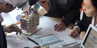 建筑师和工程师使用笔记本电脑，并在办公桌上审查蓝图