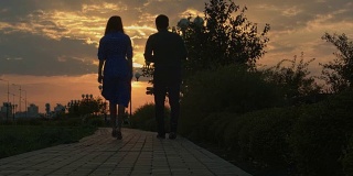 日落时分，一对年轻夫妇在秋天的公园里散步
