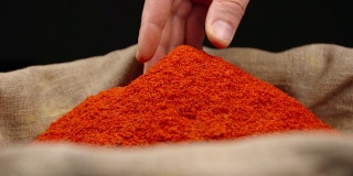 人的手从一个袋子里一堆红辣椒的顶部取下一小撮红辣椒粉