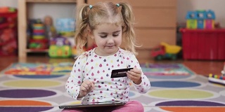 小女孩用平板电脑网上银行，用信用卡网上购物，居家生活方式。
