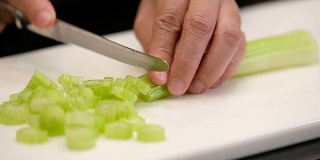 慢动作近手用刀将芹菜切在厨房的砧板上