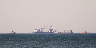 一艘货轮在朦胧的海面上，在地平线上行驶。在甲板上载运散货的多用途船。航运服务