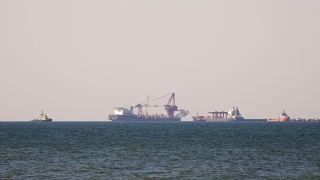 一艘货轮在朦胧的海面上，在地平线上行驶。在甲板上载运散货的多用途船。航运服务视频素材模板下载