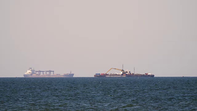 一艘货轮在朦胧的海面上，在地平线上行驶。在甲板上载运散货的多用途船。航运服务