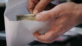 一个人拿着装着美元钞票的信封。贪污贿赂观念视频素材模板下载