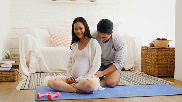 丈夫给怀孕的妻子按摩后在家训练瑜伽或锻炼，健康和怀孕的概念