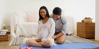 丈夫给怀孕的妻子按摩后在家训练瑜伽或锻炼，健康和怀孕的概念