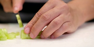 在厨房的砧板上用刀把芹菜切碎