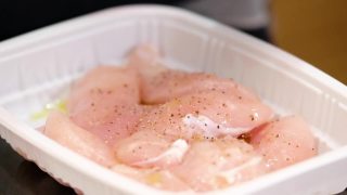 用手把生鸡肉放在厨房台面的塑料托盘里腌制视频素材模板下载
