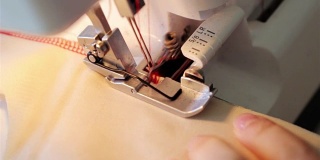 缝纫机关闭。缝牛仔宏。缝纫机的针慢动作缝着一块红色的厚布。线穿过织物。