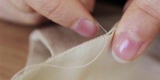 缝纫女工在缝纫机上剪布料并缝制的妇女。裁缝在机器上缝纫时用手托着布料。