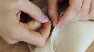 缝纫女工在缝纫机上剪布料并缝制的妇女。裁缝在机器上缝纫时用手托着布料。视频素材模板下载