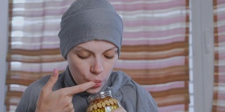 一名戴头巾的穆斯林妇女将手指浸入蜂蜜和罐子里的坚果中。从手指上吃蜂蜜。