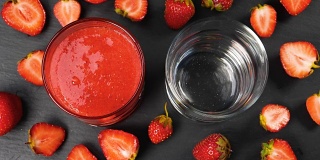 新鲜的草莓冰沙在玻璃杯中流动准备饮用
