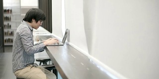 年轻的亚洲商人在工作空间使用笔记本电脑。男性用手在笔记本电脑键盘上输入密码进行登录。数字时代概念中的自由职业生活方式。
