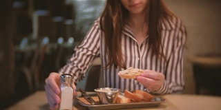 深色头发的女人在咖啡厅吃盐三明治。