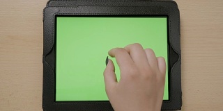 俯视图的年轻女子手触摸平板电脑绿色屏幕浏览放大和缩小