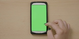 十几岁的女性使用带有色度键绿色屏幕的智能手机，在社交媒体上滑动屏幕可以放大或缩小