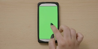 年轻女子用触屏智能手机，用手指在绿色屏幕上切换媒体内容