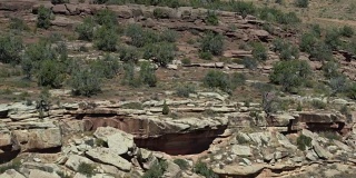 两个人在科罗拉多州大Junction沙漠的科罗拉多国家纪念碑的岩石边缘上行走的航拍照片
