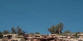 从下方航拍的两个人走在科罗拉多州大Junction沙漠的科罗拉多国家纪念碑的岩石边缘上