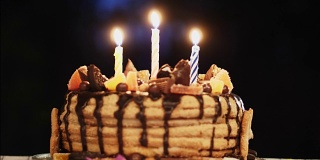 在一间黑漆漆的房间里举行生日蛋糕派对，还有三支蜡烛