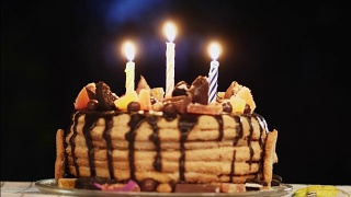 在一间黑漆漆的房间里举行生日蛋糕派对，还有三支蜡烛视频素材模板下载