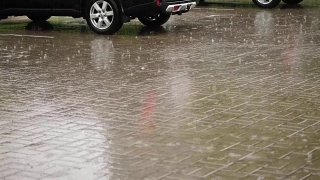 汽车在城市的停车场被淋湿了，有大雨，倾盆大雨，整个停车场都被水淹没了，大滴大滴的水滴溅进水坑里视频素材模板下载