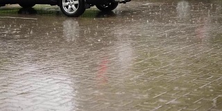 汽车在城市的停车场被淋湿了，有大雨，倾盆大雨，整个停车场都被水淹没了，大滴大滴的水滴溅进水坑里