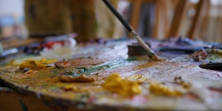 油画颜料的木制艺术调色板。在绘画前把颜色混合在一起。色彩丰富的艺术乐器。工作工具与挤出管油漆