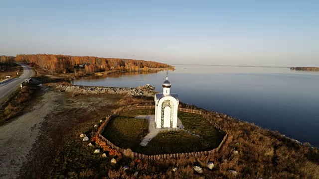 Aerial Backward flying over the small church by the lake