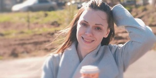 迷人的微笑年轻女子的肖像在城市公园与咖啡。